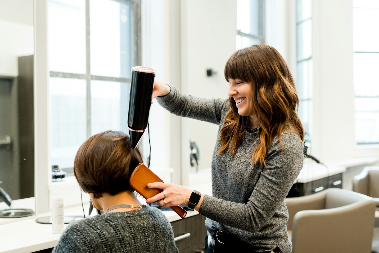 Coiffeuse réalisant une mise en forme dans un salon lumineux